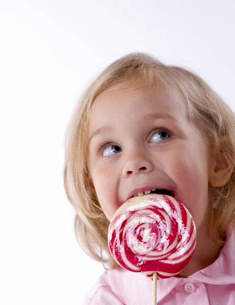 Маленькая девочка ест большой леденец — стоковое фото