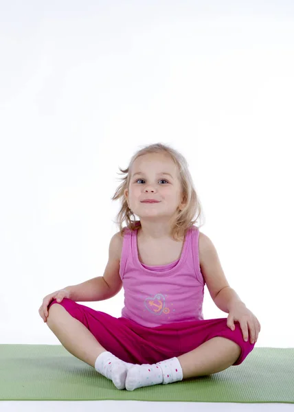 Meisje doet gymnastische oefeningen op de mat — Stockfoto