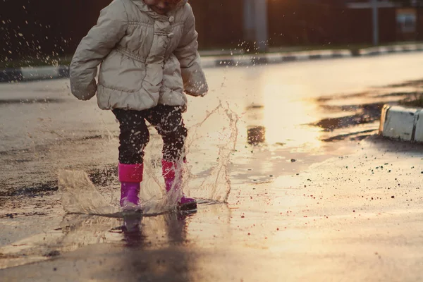 Niño saltando en el charco fangoso. primer plano de las botas —  Fotos de Stock