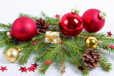 Beyaz arka planda köknar ağacı dallarıyla süslenmiş Noel süslemeleri