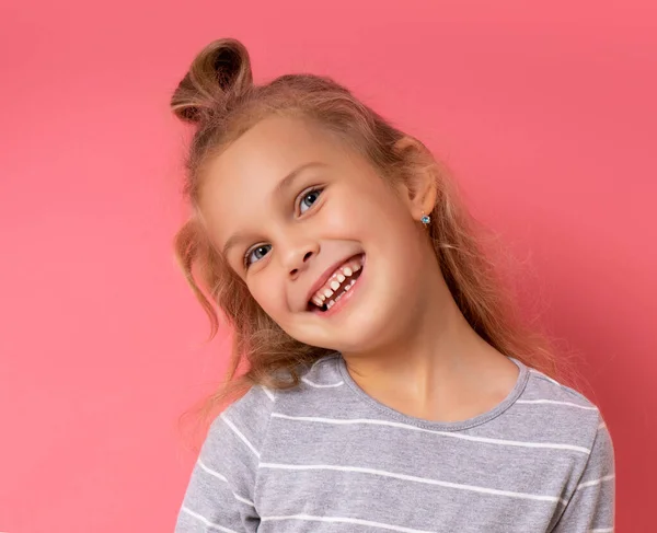 Muchacha divertida con un peinado divertido de pie sonriendo sobre un fondo rosa —  Fotos de Stock