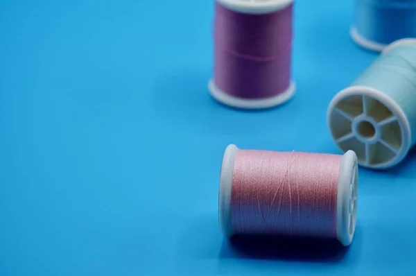 Eine Gruppe von rosa, lila, grünen und blauen Fäden auf blauem Hintergrund — Stockfoto