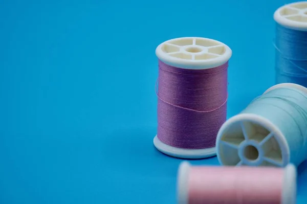 A group of purple, green, pink and blue thread on the blue background — Stock Photo, Image