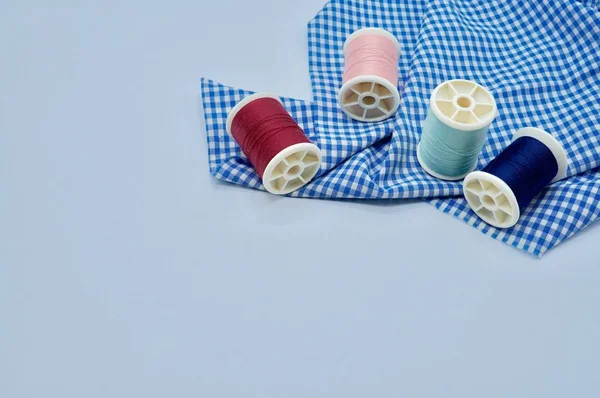 Pink, green, red and blue threads on blue checked fabric — Stock Photo, Image