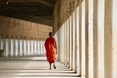 Myanmar, Bagan 'daki Shwezigon tapınağının koridorunda yürüyen bir Budist rahibin arka görüntüsü.