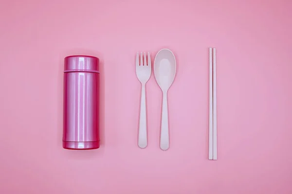 ピンクの背景にピンクのスプーン、フォーク、箸、魔法瓶、フラットレイアウト — ストック写真