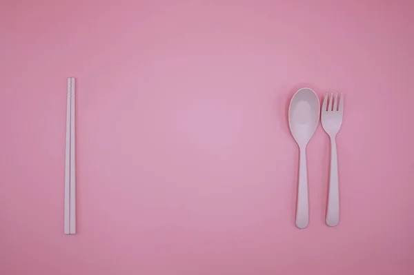 Rózsaszín villa, kanál és evőpálcikák a rózsaszín háttér — Stock Fotó