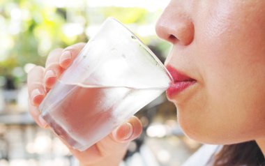 A close up view of young woman drinking water from a glass in the garden