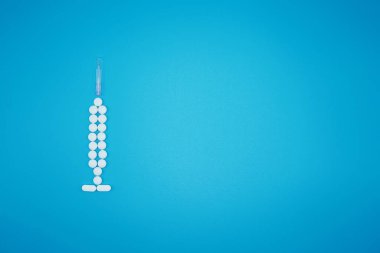 Beyaz haplar mavi arka planda bir şırınga haline geliyor.