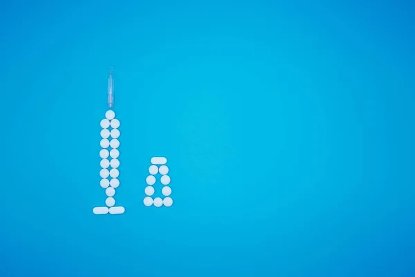 Weiße Pillen als Spritze auf blauem Hintergrund — Stockfoto