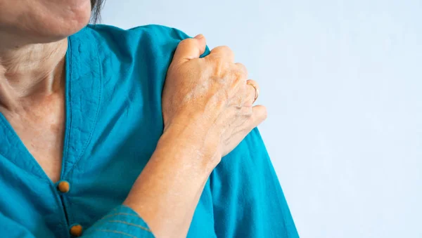 Een oude vrouw in blauwe blouse krijgt schouderpijn, witte backgro — Stockfoto