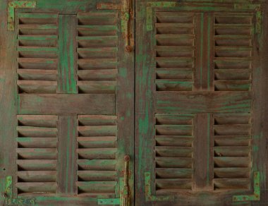 Paslı menteşeli eski, yeşil ve kahverengi bir ahşap pencere.