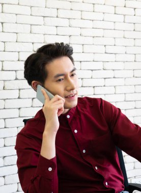 Kendine güvenen Asyalı genç bir işadamı çayın üzerinde oturuyor.