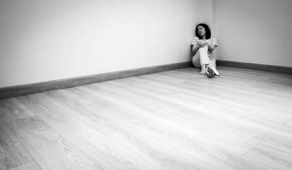 Una joven mujer triste con cara infeliz sentada en la esquina de la — Foto de Stock