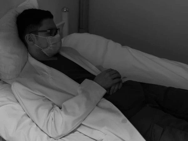 Mladý Lékař Zakrývající Obličej Chirurgickou Maskou Pocit Únavy Spaní Posteli — Stock fotografie