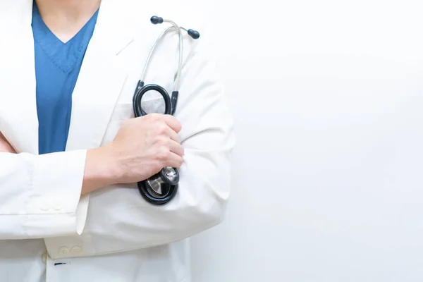 A specialist doctor in blue scrub uniform with white gown holding a stethoscope in the hospital (white background)