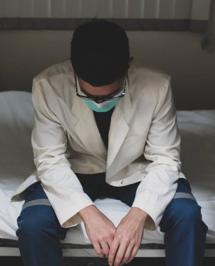 Beyaz önlüklü genç bir doktor, hastanedeki odada otururken strese giriyor.