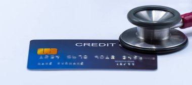 Beyaz arka plandaki kredi kartında steteskop var.