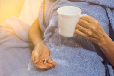 Hastalığı tedavi etmek için ilaç ve su alan bir hasta (sağ ele odaklanın)