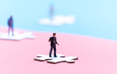 Yapboz parçalarının üzerinde duran minyatürler diğer minyatürlerle mesafeyi koruyorlar, koronavirüsün yayılmasını önlemek için sosyal mesafeyi koruyorlar (seçici odaklanma)