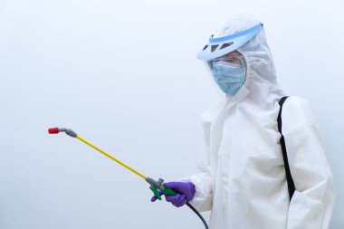Beyaz giysi maskesi ve yüz kalkanı da dahil olmak üzere kişisel koruyucu ekipman işçisi Coronavirus enfeksiyonunu kontrol etmek için dezenfektan (elde odaklanın)