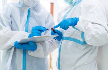 Beyaz takım elbise, maske, yüz kalkanı ve eldivenler de dahil olmak üzere iki doktor koronavirüs patenti tedavisi hakkında tartışıyorlar. covid-19, hastane, karantina birimi konsepti