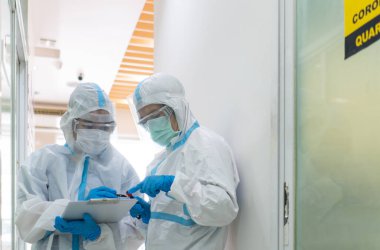 Beyaz takım elbise, maske, yüz kalkanı ve eldivenler de dahil olmak üzere iki doktor koronavirüs patenti tedavisi hakkında tartışıyorlar. covid-19, hastane, karantina birimi konsepti