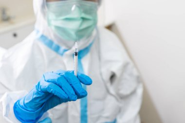 Kişisel koruyucu ekipmanlı bir doktor enjeksiyon için aşı hazırlıyor. covid-19, koronavirüs, aşı, aşılama, tıbbi, sağlık konsepti
