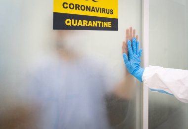 Covid-19 enfeksiyonu olan bir hasta negatif odada karantinaya alınırken, bir doktor tedavi ve destek veriyor. Coronavirus, tıbbi ve sağlık hizmetleri kavramı