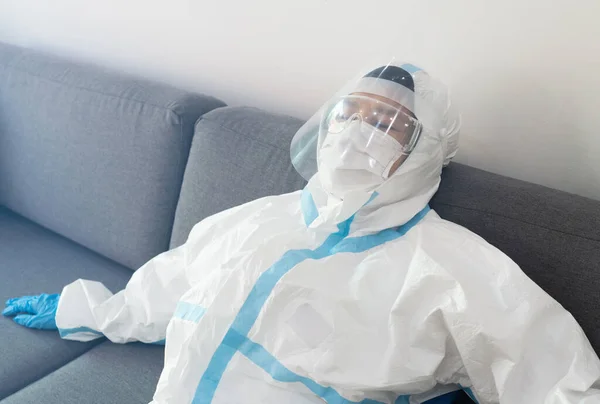 A docotor in personal protective equipment is sleeping on the couch in the hospital. covid-19, coronaviurs, medical, burnout, healthcare, tired, work hard, depression concept