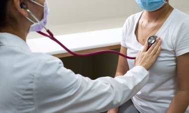 Hastanedeki klinikte ateşi ve öksürüğü olan bir hastanın akciğerini incelemek için steteskop kullanan bir kadın doktor. tıbbi konsept