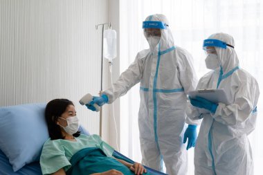 Kişisel pretective ekipman alanında iki doktor mu yoksa salgın sırasında hastanede koronavirüs enfeksiyonu olan Asyalı kadın hastayı tedavi etmek mi? tıbbi konsept