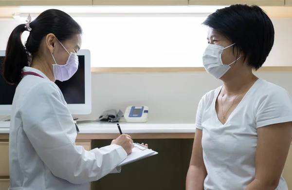 病院の診療所で病気になっている患者の病歴をアジア人女医が取っている 医療の概念 — ストック写真