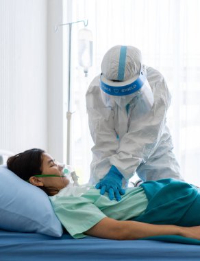 Kişisel koruyucu ekipman ya da ppe doktor Coperid-19 ya da koronavirüs enfeksiyonu olan ve karantina ünitesinde aniden çöken hastaya kalp masajı veya kalp masajı uygular.