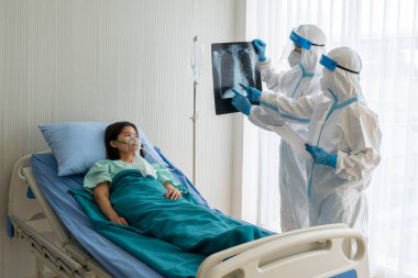 Kişisel koruyucu ekipmanlarda çalışan doktorlar ya da Asyalı kadın hastaların göğüs röntgenlerine bakan doktorlar ya da hastanedeki izolasyon ünitesinde koronavirüs enfeksiyonu olanlar. tıbbi konsept