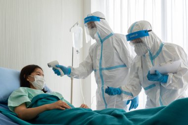 Kişisel pretective ekipman alanında iki doktor mu yoksa salgın sırasında hastanede koronavirüs enfeksiyonu olan Asyalı kadın hastayı tedavi etmek mi? tıbbi konsept
