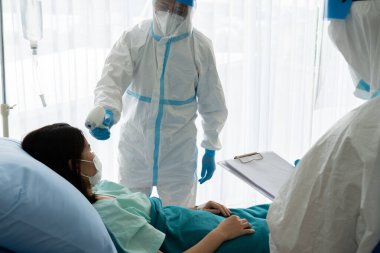Kişisel pretective ekipman alanında iki doktor mu yoksa salgın sırasında hastanede koronavirüs enfeksiyonu olan Asyalı kadın hastayı tedavi etmek mi? tıbbi konsept