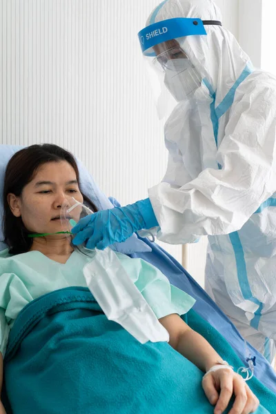 個人用保護具や銅製の医師は パンデミック時に病院の隔離室でコビト19またはコロナウイルス感染症を患っているアジアの女性に袋で酸素マスクを与えます 医療の概念 — ストック写真
