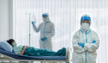 Kişisel pretective ekipman alanında iki doktor mu yoksa salgın sırasında hastanede koronavirüs enfeksiyonu olan Asyalı kadın hastayı tedavi etmek mi? tıbbi konsept