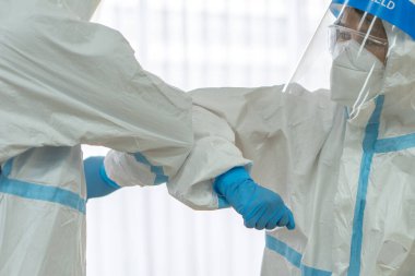 Doktor ve hemşire kişisel koruyucu teçhizat ya da ppe hastanede covid-19 ya da koronavirüs salgını sırasında dirseğine dokunarak birbirlerini selamlıyorlar. Sosyal uzaklık kavramı
