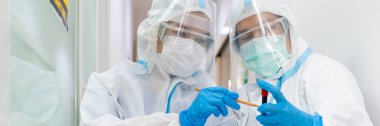 Beyaz takım elbise, maske, yüz kalkanı ve eldivenler de dahil olmak üzere kişisel koruyucu ekipman içinde doktor ve hemşire pankartları koronavirüsle patenin tedavisi hakkında tartışıyorlar. covid-19, hastane, karantina birimi konsepti