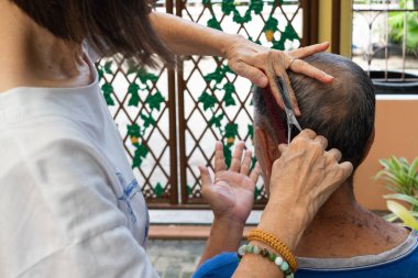 Bir kadın, kocasına evde tek başına saç kesimi yapıyor. Kovid-19 ya da koronavirüs salgını sırasında. Çünkü berber dükkanı kapalı..