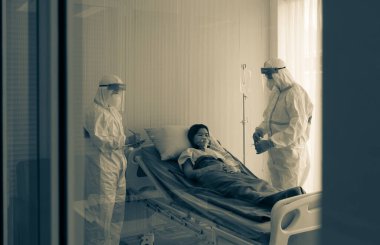 Kişisel pretective ekipman alanında iki doktor mu yoksa salgın sırasında hastanede koronavirüs enfeksiyonu olan Asyalı kadın hastayı tedavi etmek mi? tıbbi konsept