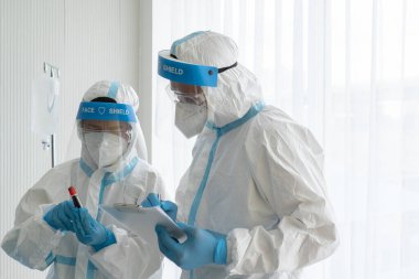 Doktor ve hemşire kişisel koruyucu ekipmanlarda ya da Pen hastanede kovid 19 ya da koronavirüs enfeksiyonu olan bir hastanın kan testi tüpünü gösteriyor. tıbbi konsept