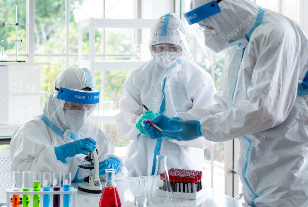 scientists in personal protective equipment or ppe doing research and experiment to find drugs to treat covid-19 or coronavirus infection in the lab