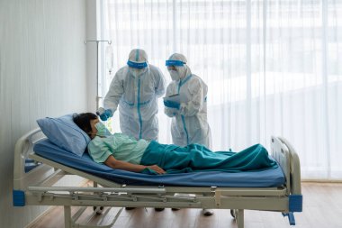 Kişisel pretective ekipman doktor ve hemşire ya da salgın sırasında hastanede karantina altında tutulan kovid-19 veya koronavirüs enfeksiyonu olan yaşlı Asyalı kadın hastayı tedavi etmek. tıbbi konsept