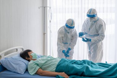 Kişisel pretective ekipman doktor ve hemşire ya da salgın sırasında hastanedeki izolasyon ünitesinde kovid 19 veya koronavirüs enfeksiyonu olan Asyalı kadın hastayı tedavi etmek. tıbbi konsept