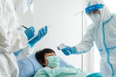 Kişisel pretective ekipman doktor ve hemşire ya da salgın sırasında hastanede karantina altında tutulan kovid-19 veya koronavirüs enfeksiyonu olan yaşlı Asyalı kadın hastayı tedavi etmek. tıbbi konsept