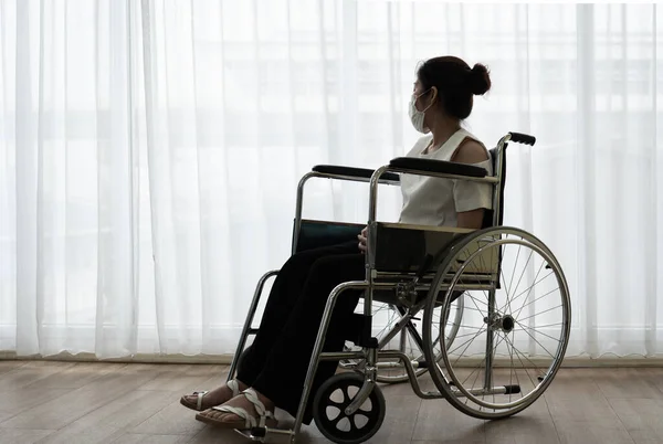 Asian young handicapped woman with sad and hopeless feeling sitting on the wheelchair alone in the house. handicap and disability concept