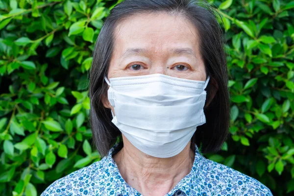 顔のマスクをしたアジア系高齢女性の肖像写真は 自宅での隔離中にCovid 19またはコロナウイルス感染を避けるためである 社会的距離と新しい通常のライフスタイルコンセプト — ストック写真